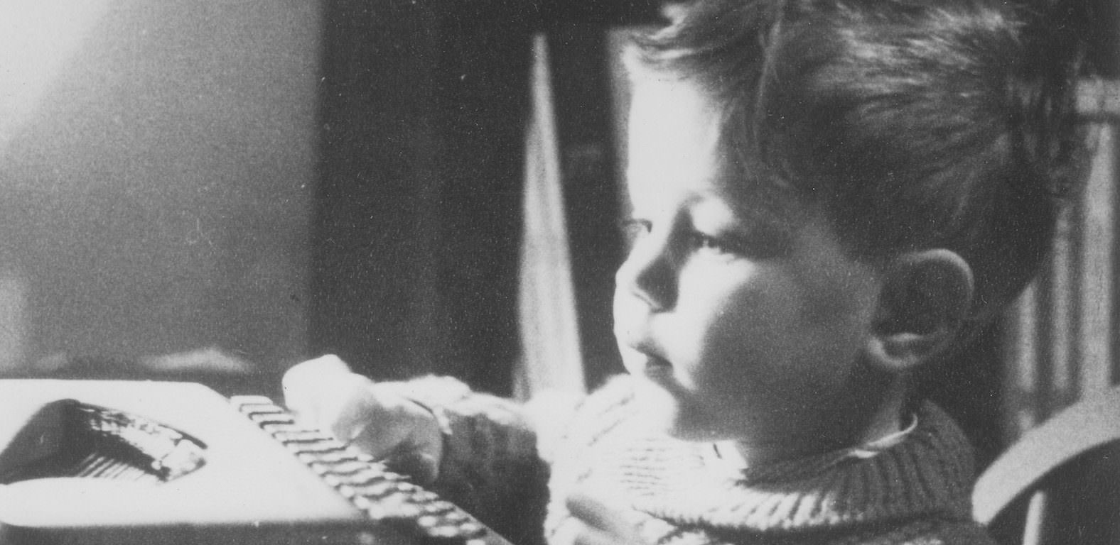 A young boy typing on an old typewriter